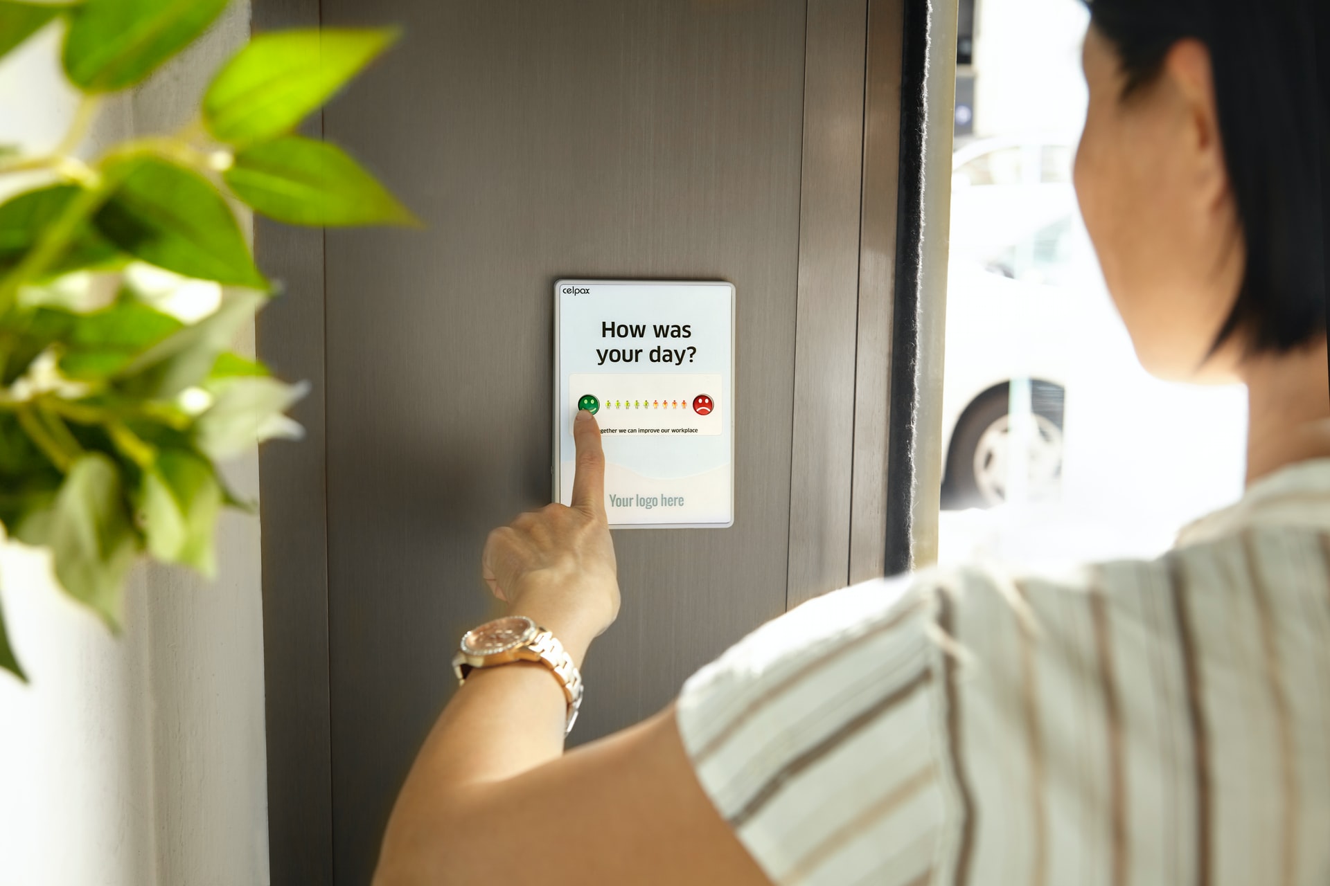 Female employee pressing a green button to give feedback to a survey